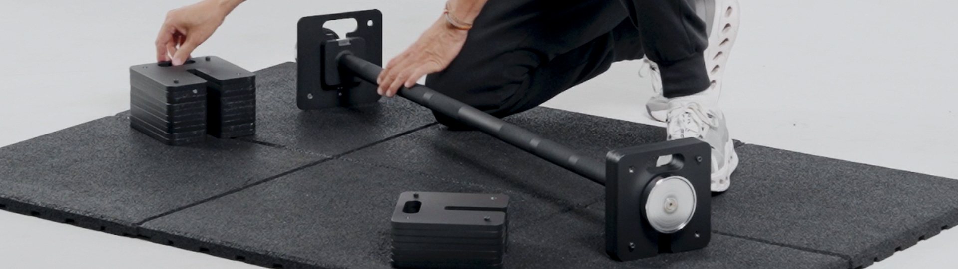 Two 100lb black adjustable dumbbells on a workout bench.