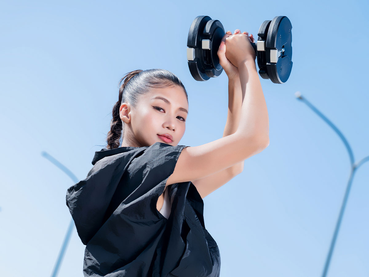 Woman lifting 27.5lb black adjustable dumbbells from T9 series during an intense workout