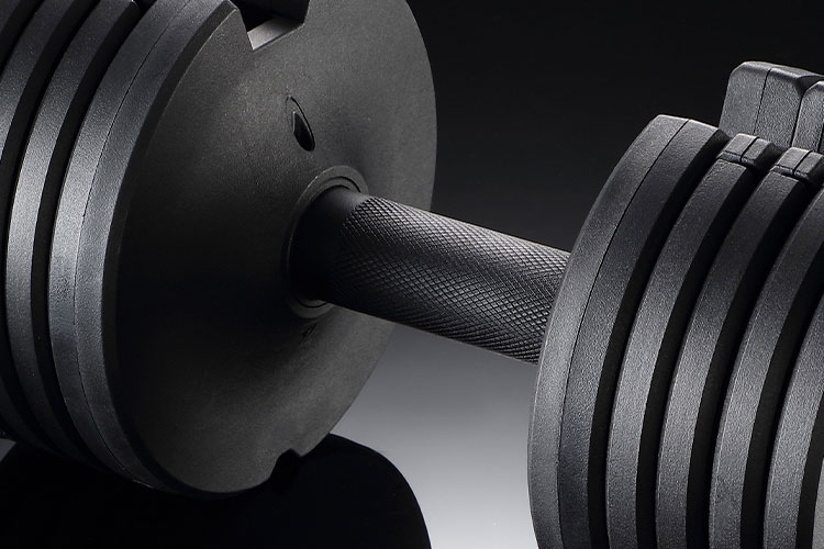 Woman lifting 25lb black adjustable dumbbell during a strength training session