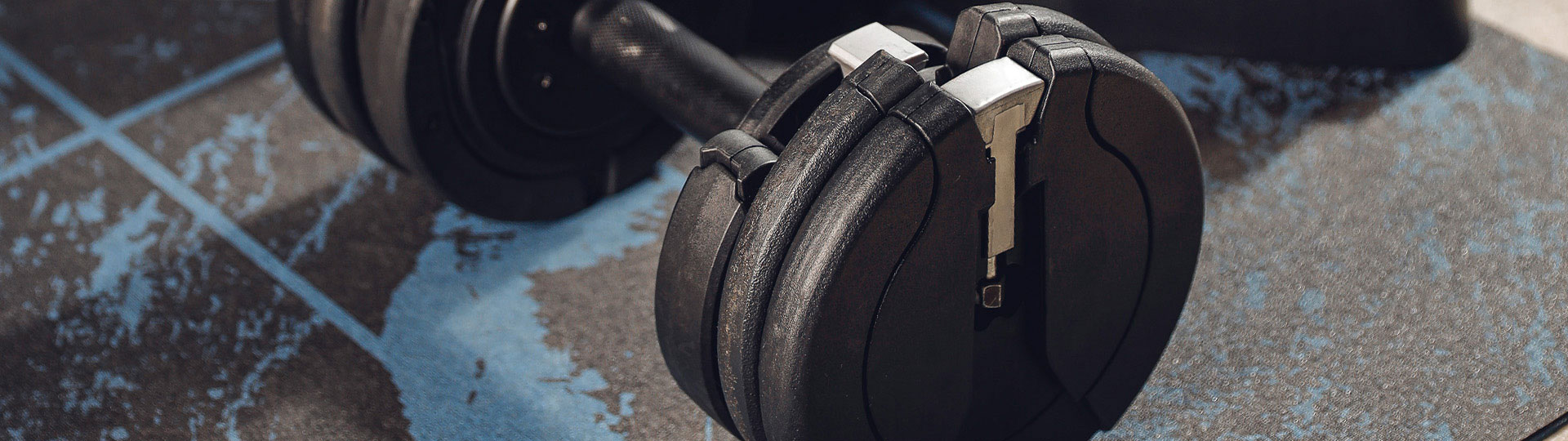 Close-up of a black adjustable dumbbell on a workout mat from the T9 series.